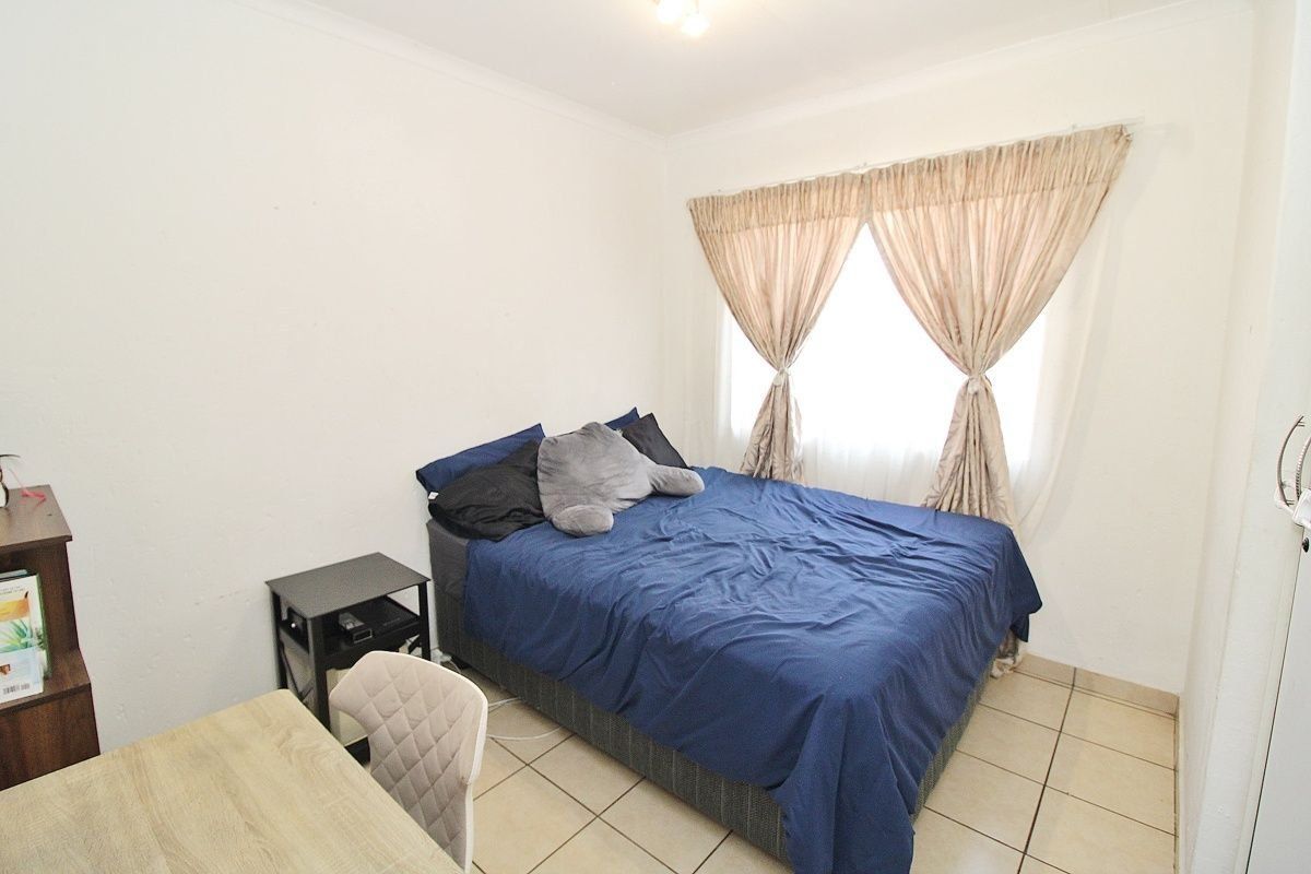 A functional bedroom featuring tiled flooring and a built-in cupboard, offering a neutral space ready for personalization.