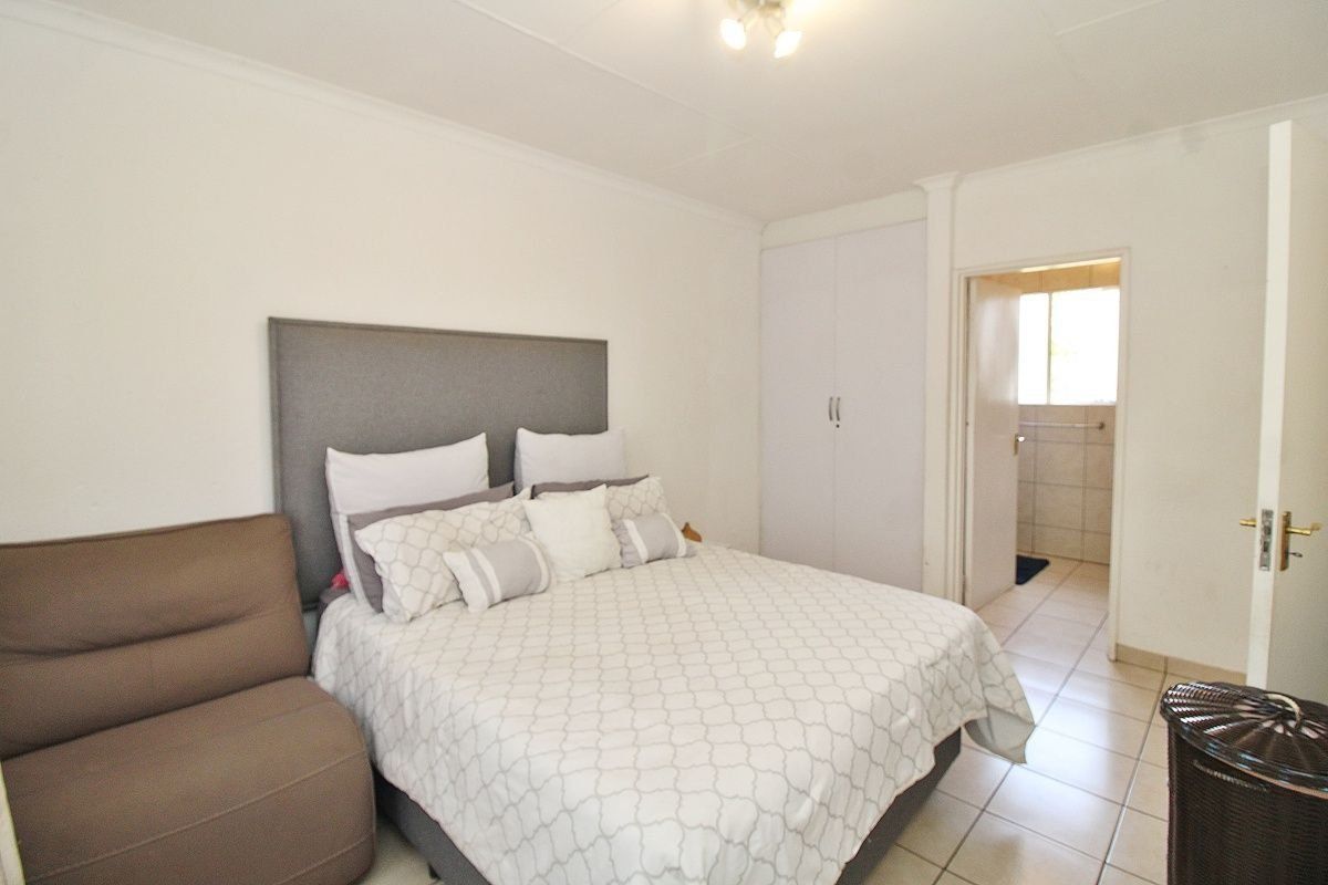 A bedroom featuring tiled flooring, built-in wardrobe storage, and an adjoining en-suite bathroom.