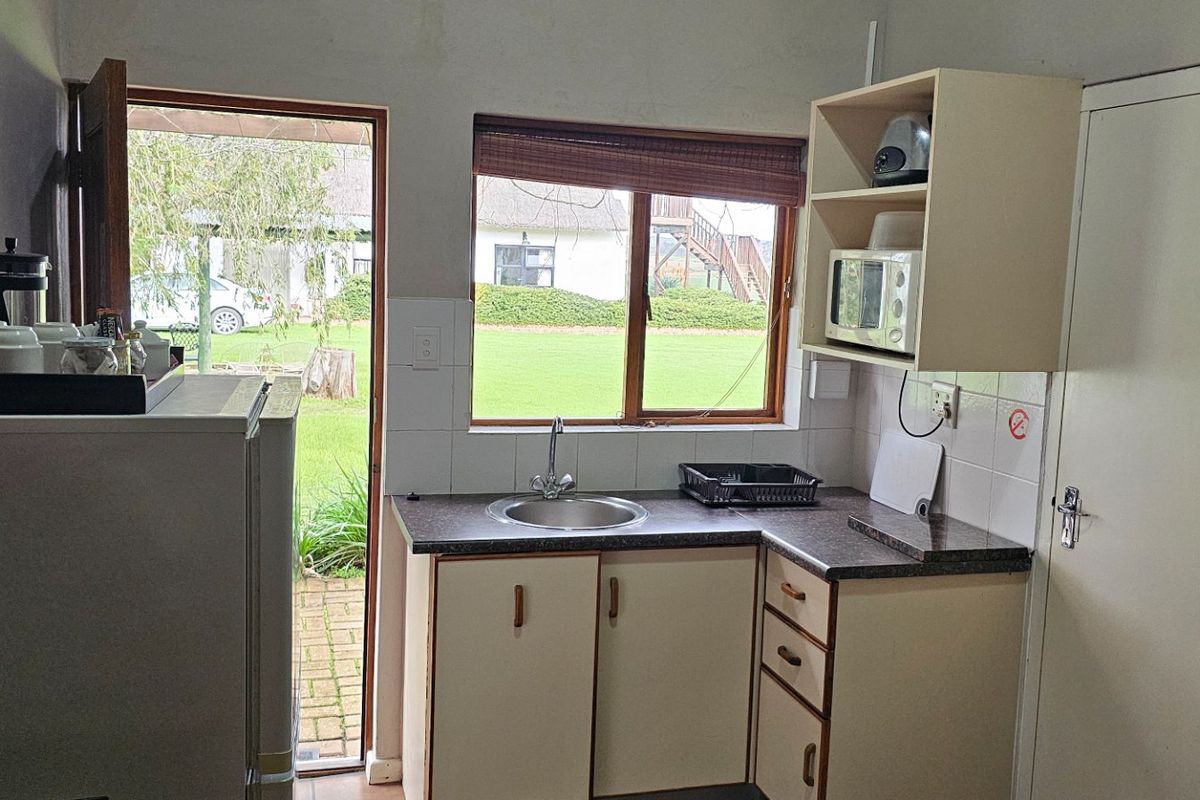 Compact kitchen area featuring built-in cabinetry, laminate countertops, a stainless steel sink, and direct access to the outdoor garden area.