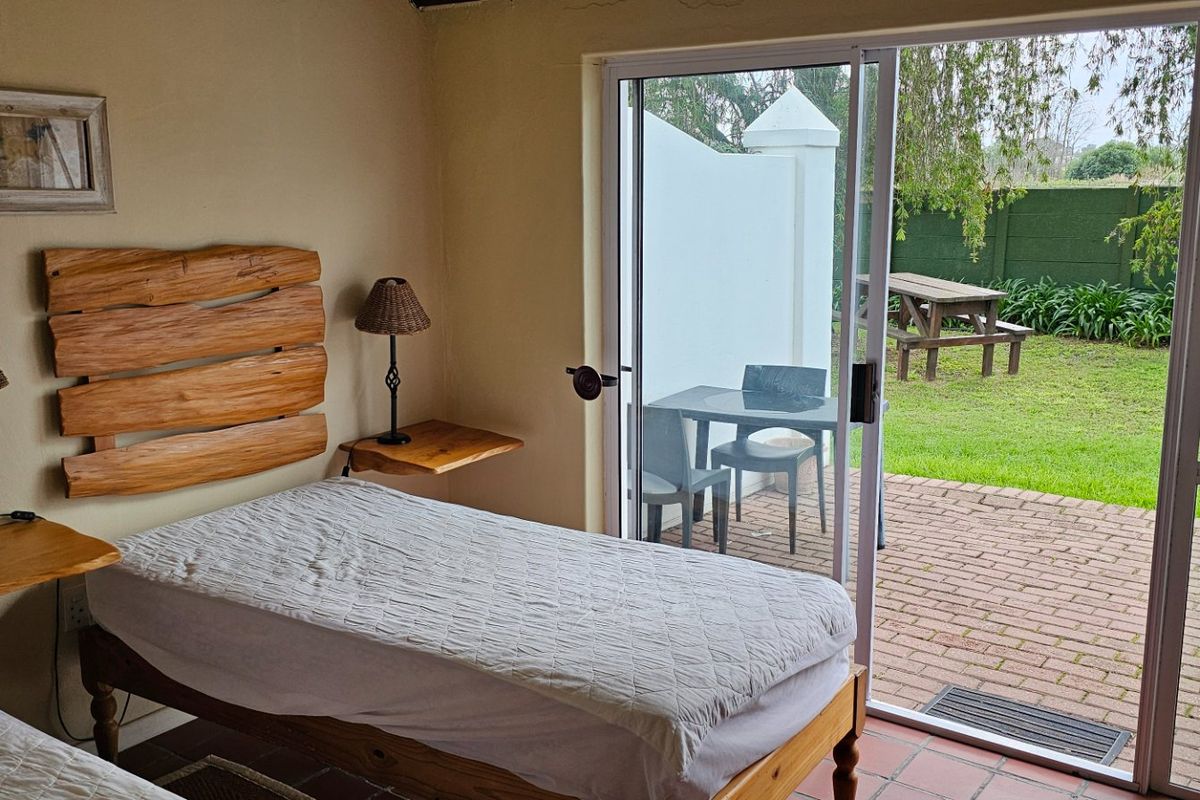 Bedroom featuring tiled flooring and a large sliding glass door providing direct access to a private patio and garden area.