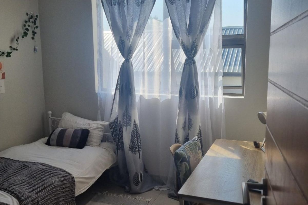 A well-lit bedroom featuring tiled flooring, neutral wall finishes, and a window with natural light.