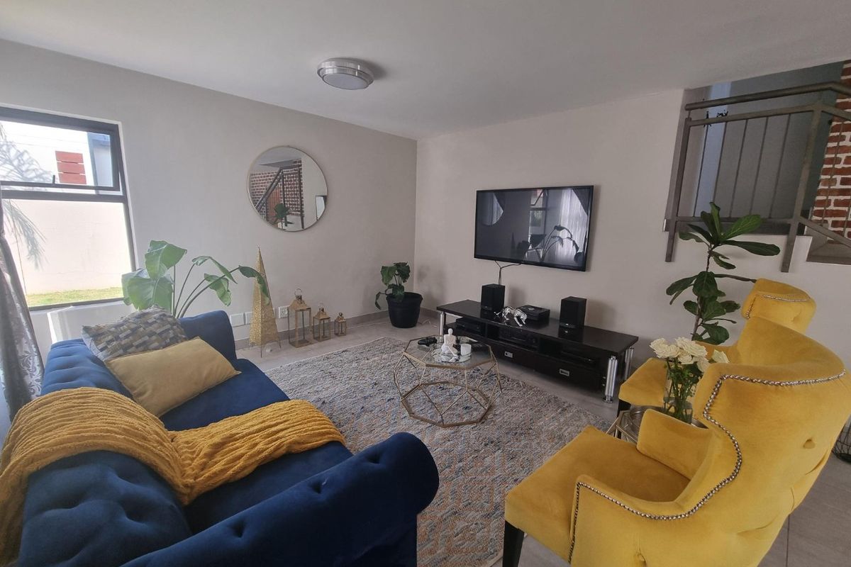 A well-maintained living room featuring neutral wall tones, tiled flooring, and a staircase with a metal railing.