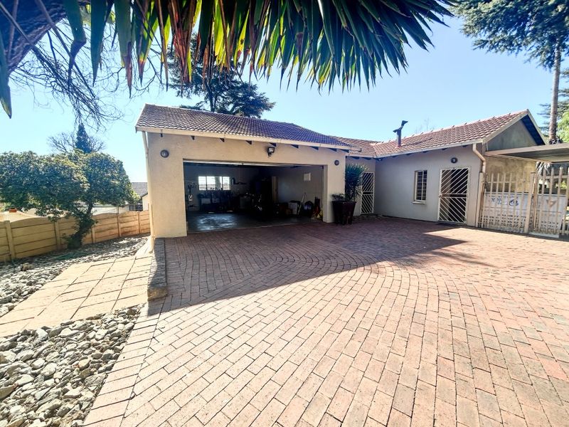Front exterior view of the property featuring a paved driveway, double garage, and secure entrance with security gates.