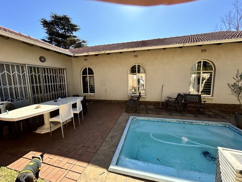 Outdoor pool area featuring brick paving, arched windows, and security gates, providing a functional space for outdoor relaxation and entertainment.
