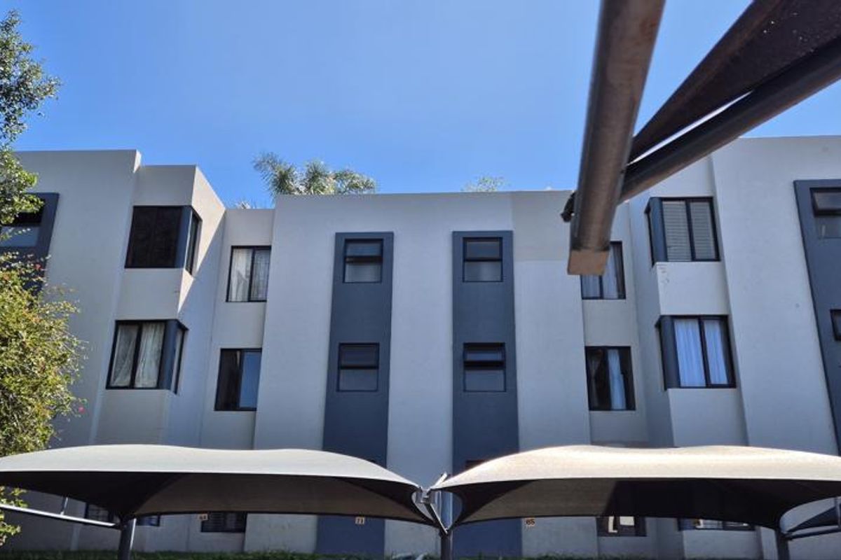 Exterior view of a multi-story townhouse complex featuring modern facade finishes and installed shade cloth carports.
