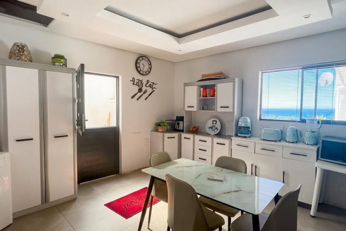 A functional kitchen area featuring white built-in cabinetry, tiled flooring, and a recessed ceiling, with direct access to an exterior door.