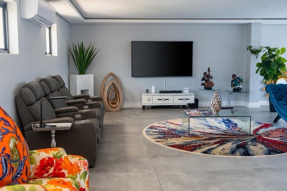 Spacious living room featuring large format floor tiles, recessed ceiling lighting, and a wall-mounted air conditioning unit in a modern, well-maintained setting.