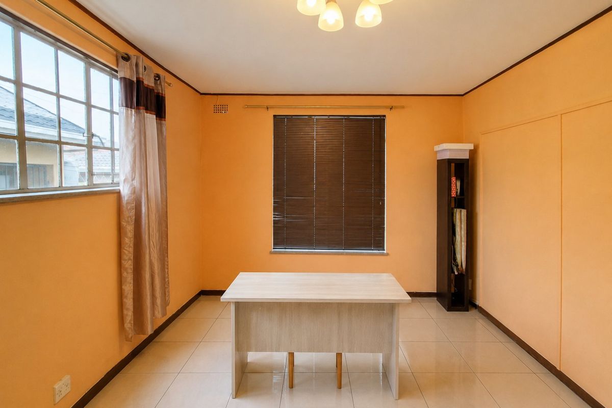A bright, empty bedroom featuring tiled flooring, a built-in cupboard, and natural light through windows with fitted blinds.