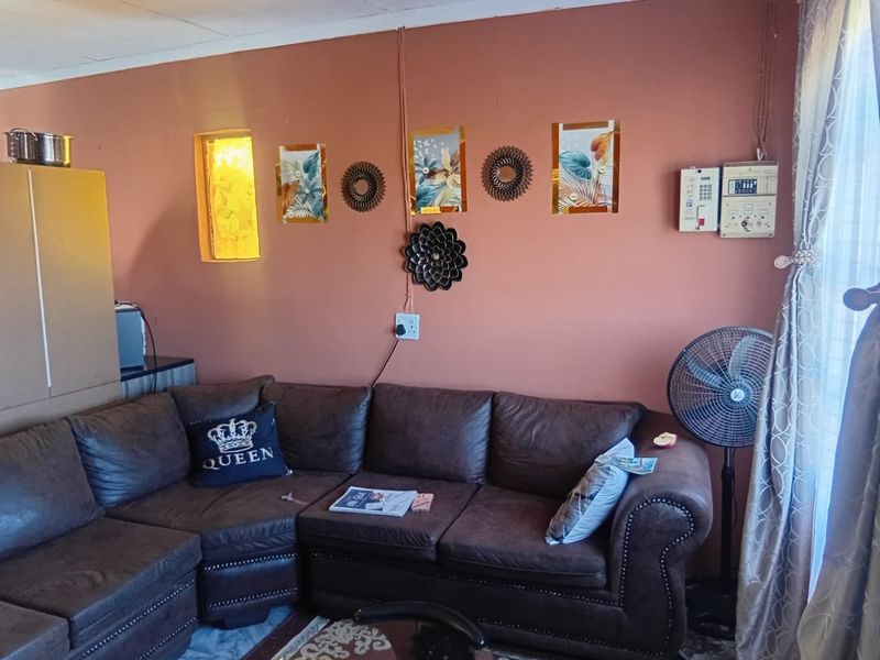 A living room featuring terracotta-toned walls, surface-mounted electrical conduits, and an integrated alarm system keypad.