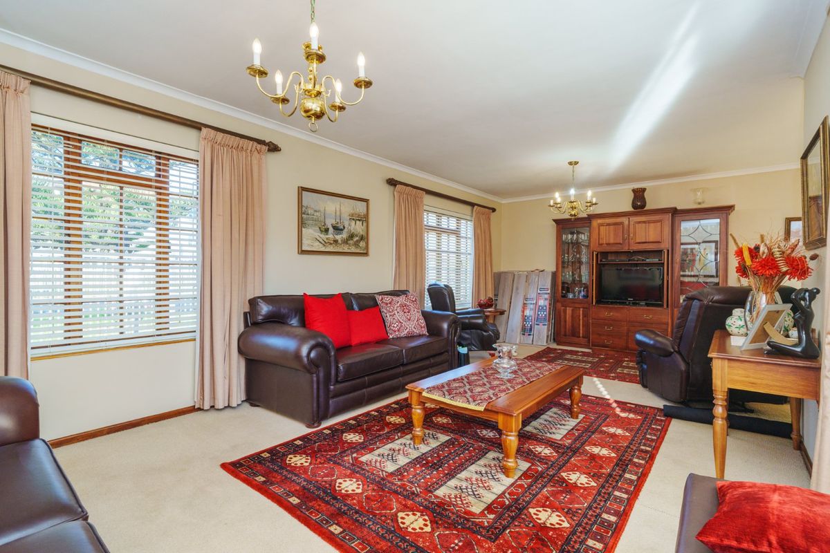 A spacious living room featuring neutral carpeting, classic brass chandeliers, and built-in wooden cabinetry, offering a traditional and comfortable living space.