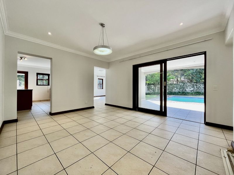 Spacious, light-filled living area featuring neutral ceramic tile flooring, recessed lighting, and large sliding glass doors providing direct access to the patio and pool.