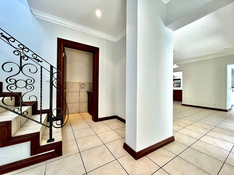 Spacious entrance hall featuring tiled flooring, a decorative wrought iron staircase, and clean neutral finishes leading into the main living areas.