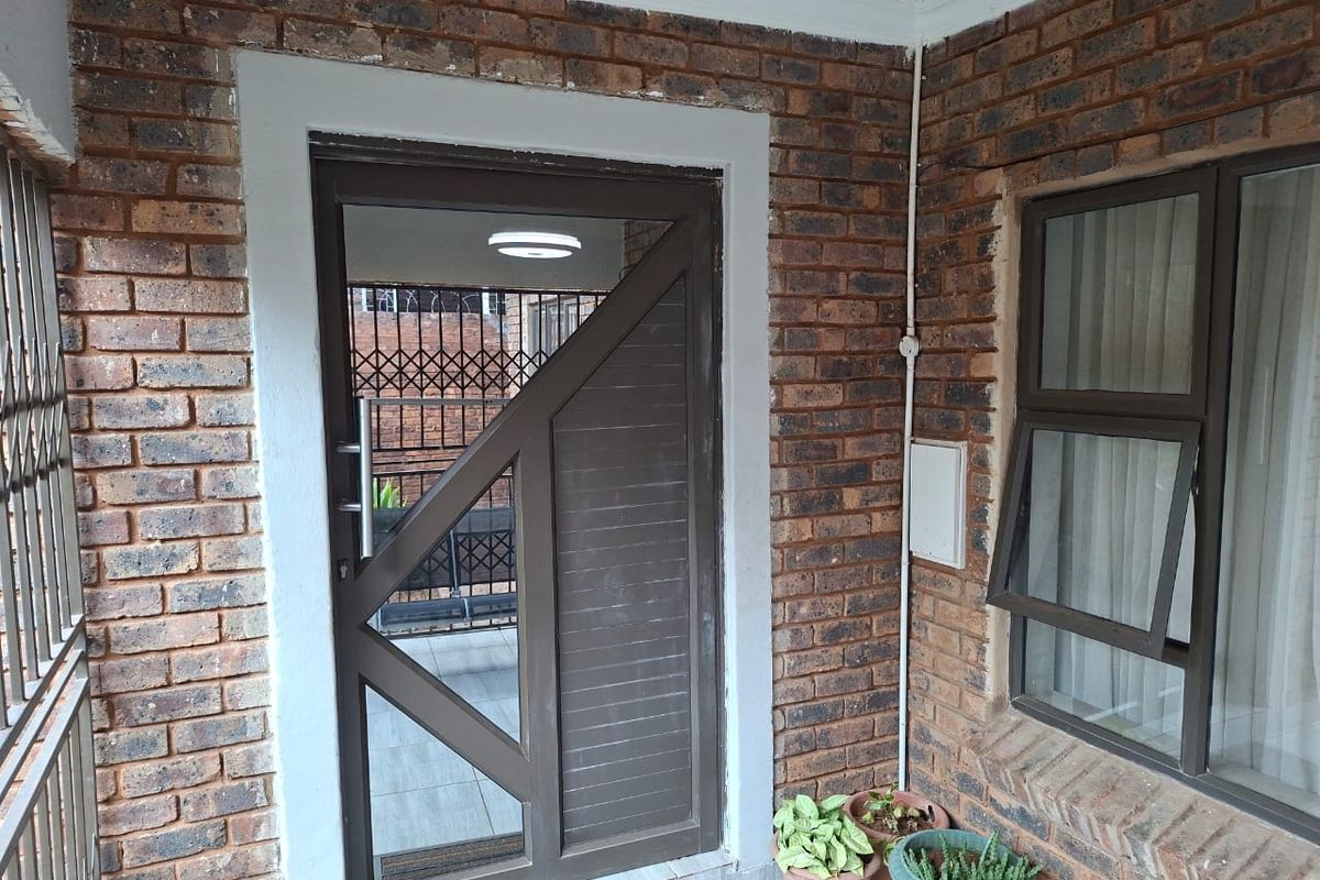 Entrance area featuring face brick walls, a modern security door, and aluminium window frames.