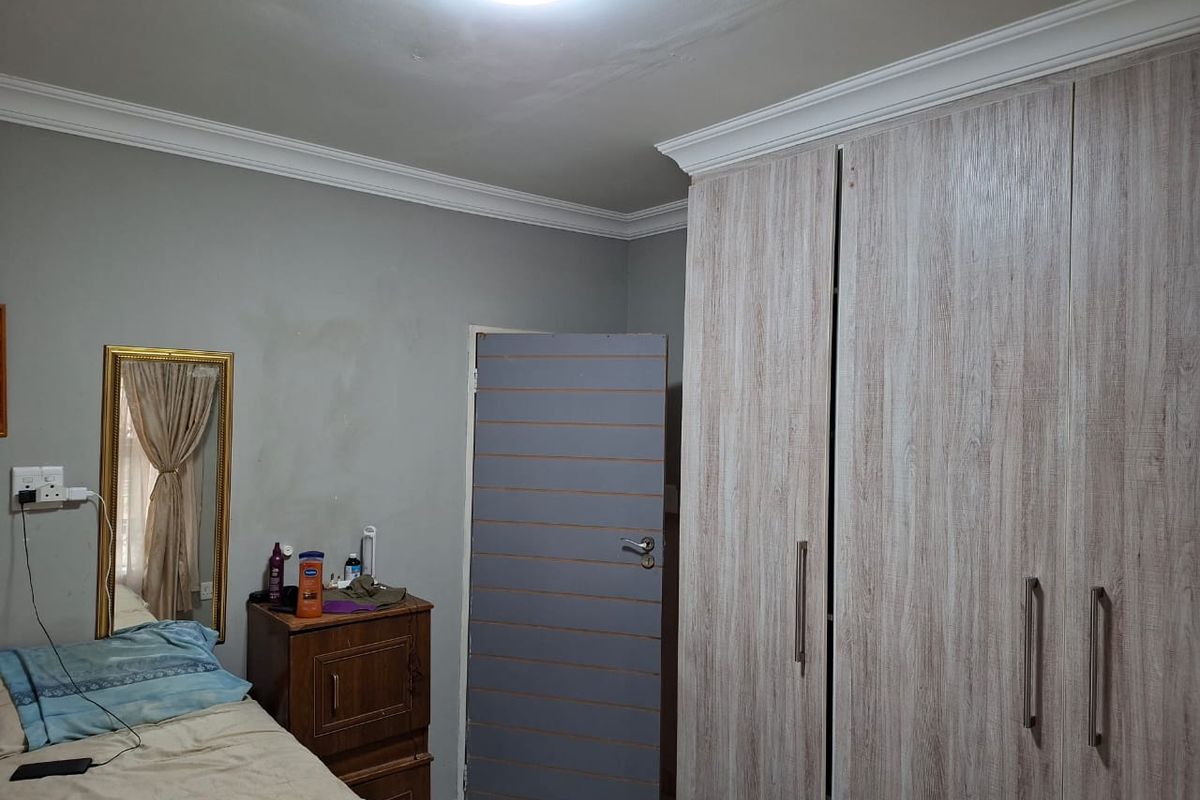 A bedroom featuring built-in wood-grain cupboards, crown molding, and neutral wall finishes.
