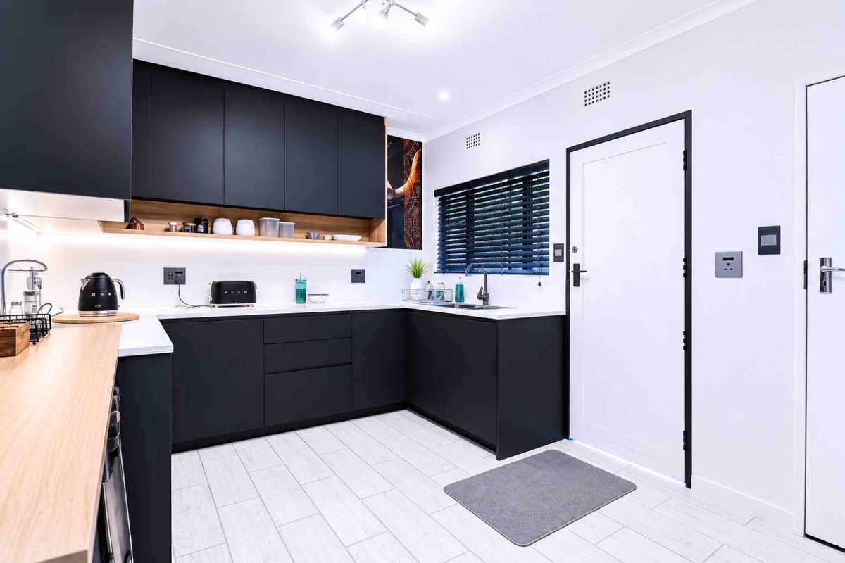 Modern kitchen featuring matte black cabinetry, white stone countertops, integrated lighting, and high-quality finishes in a clean, contemporary design.