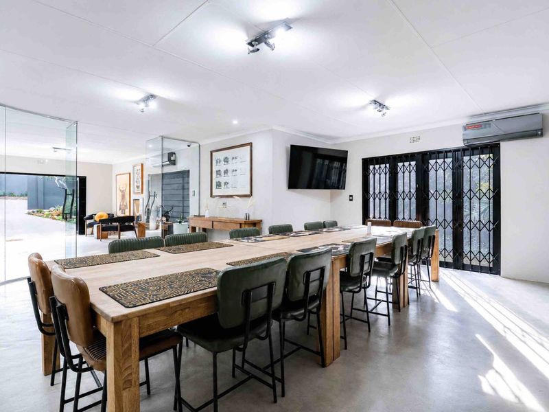 Spacious dining area featuring polished concrete floors, modern track lighting, and direct access to an outdoor patio through secure glass doors.