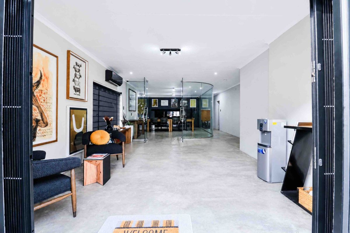 Modern open-plan living area featuring polished concrete floors, a distinctive curved glass partition, and contemporary lighting fixtures.