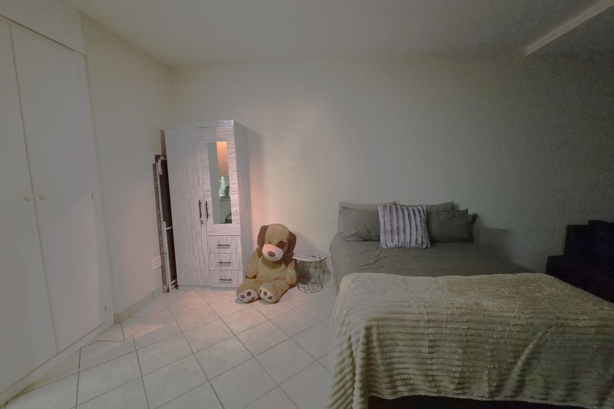 A bedroom featuring tiled flooring and a built-in wardrobe, providing a functional space with neutral finishes.
