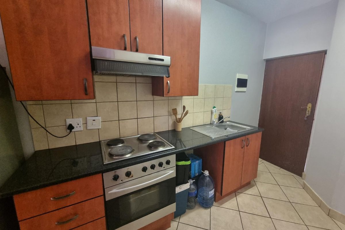 A functional kitchen featuring laminate cabinetry, granite countertops, an electric stove with extractor fan, and a stainless steel sink with tiled backsplash.