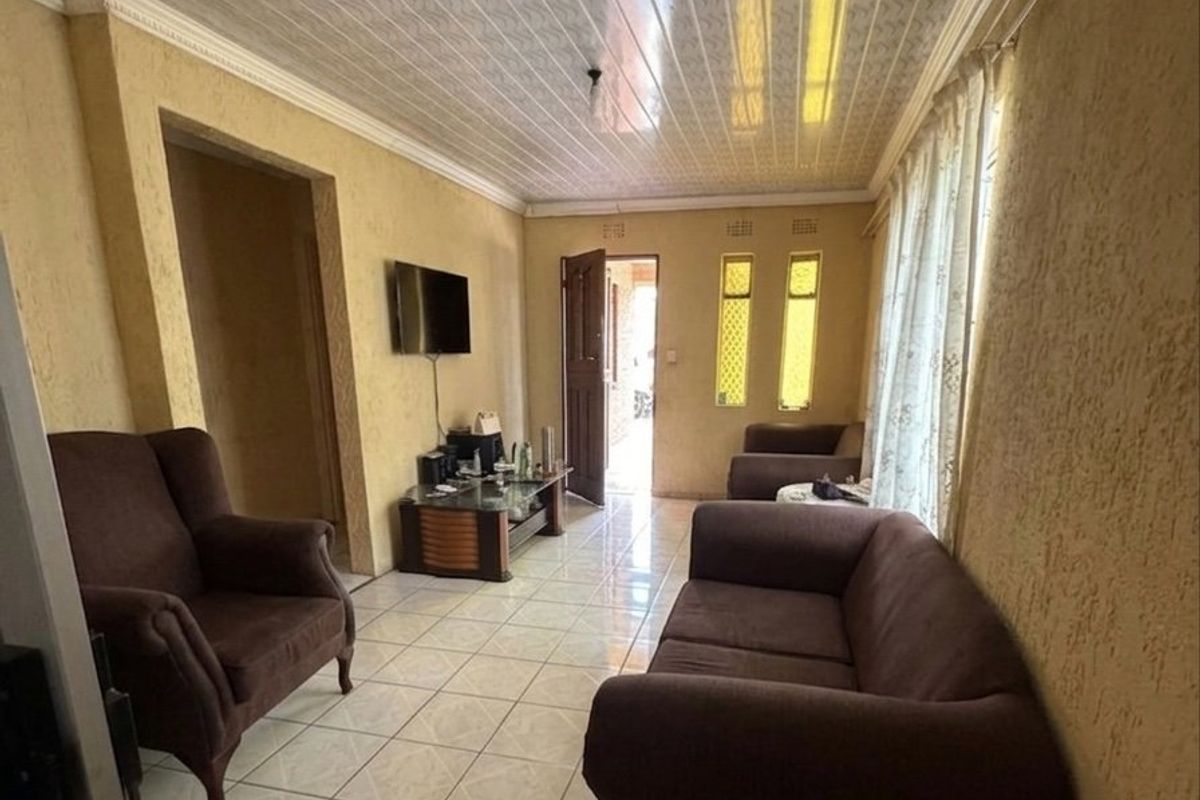 A living room featuring tiled flooring, textured walls, and a PVC panel ceiling, offering a functional space with potential for modern updates.