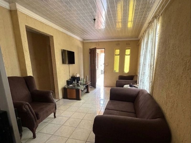 A living room featuring tiled flooring, textured walls, and a PVC panel ceiling, offering a functional space with potential for modern updates.