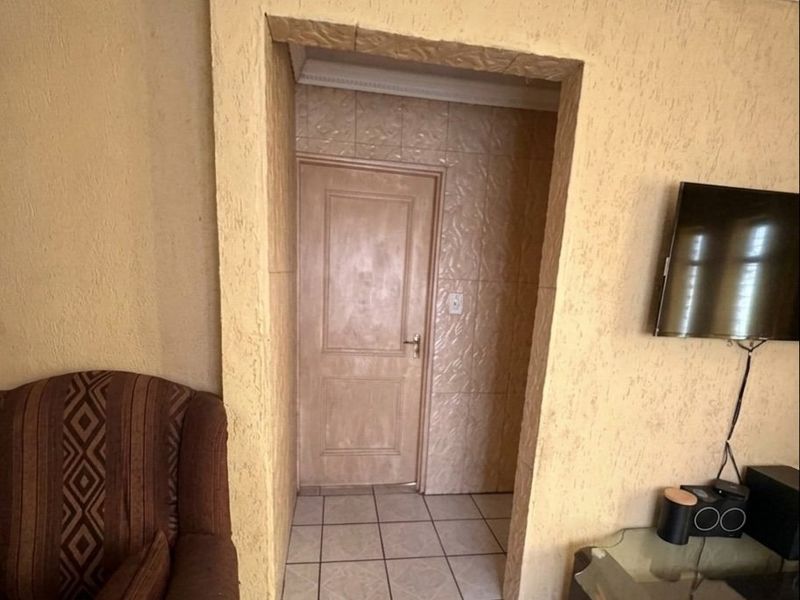 Living area featuring textured wall finishes, tiled flooring, and a doorway leading to an adjacent room.