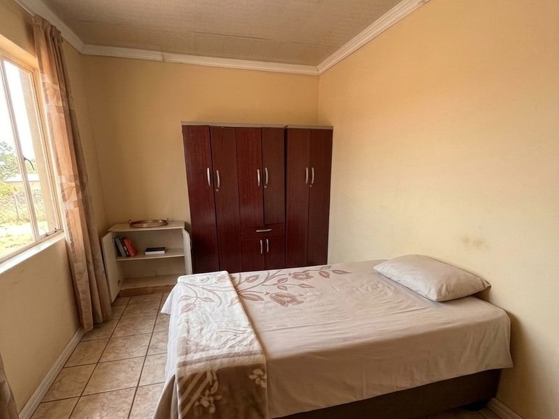 A bedroom featuring tiled flooring, a built-in wardrobe, and ceiling cornice. The room requires cosmetic updates to improve its overall condition.