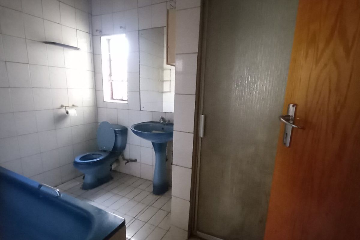 A dated bathroom featuring blue sanitaryware, a separate shower enclosure, and tiled finishes, offering significant potential for a modern renovation.