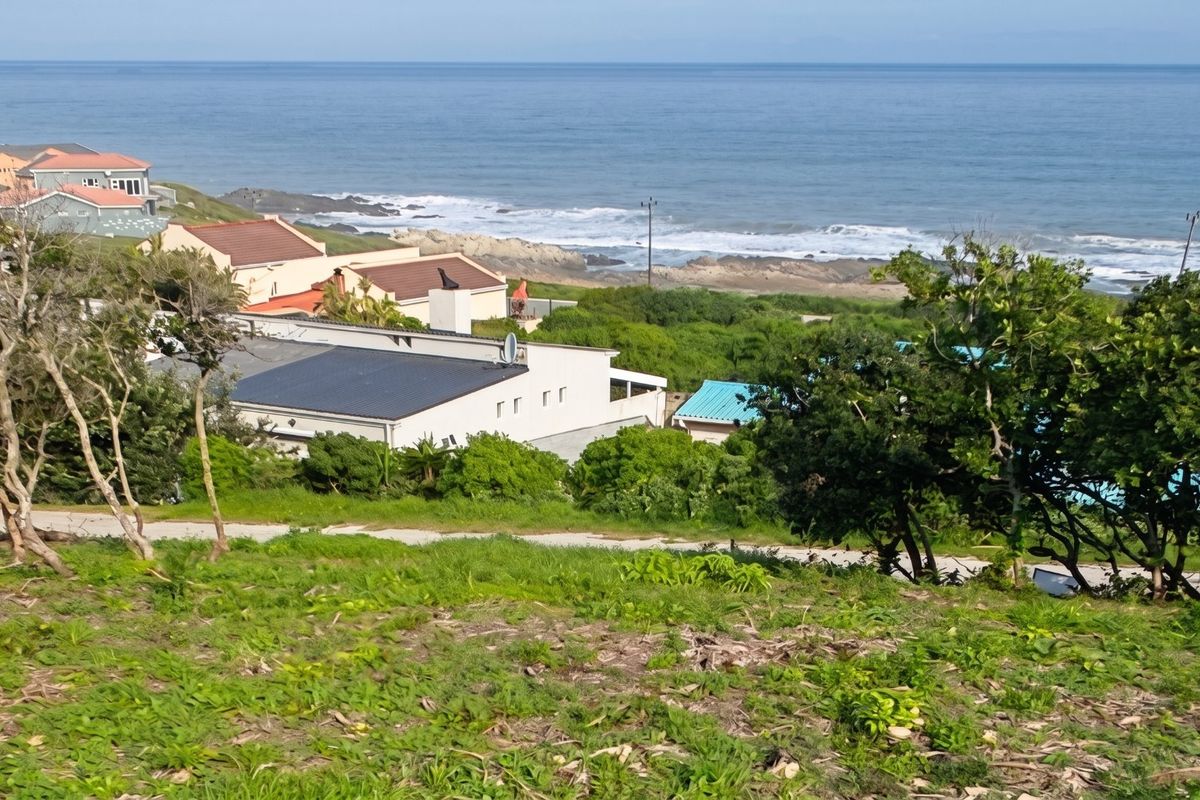 A scenic elevated view overlooking the coastline, ocean, and surrounding residential properties from the vacant land plot.