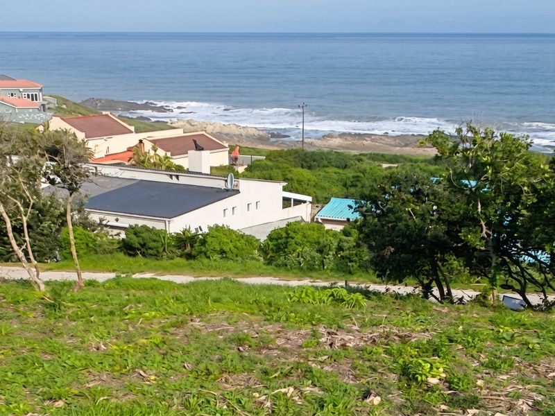 A scenic elevated view overlooking the coastline, ocean, and surrounding residential properties from the vacant land plot.