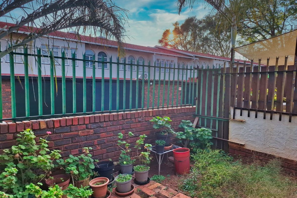 A private rear courtyard area featuring brick paving, a brick boundary wall, and metal security fencing, offering a functional outdoor space.
