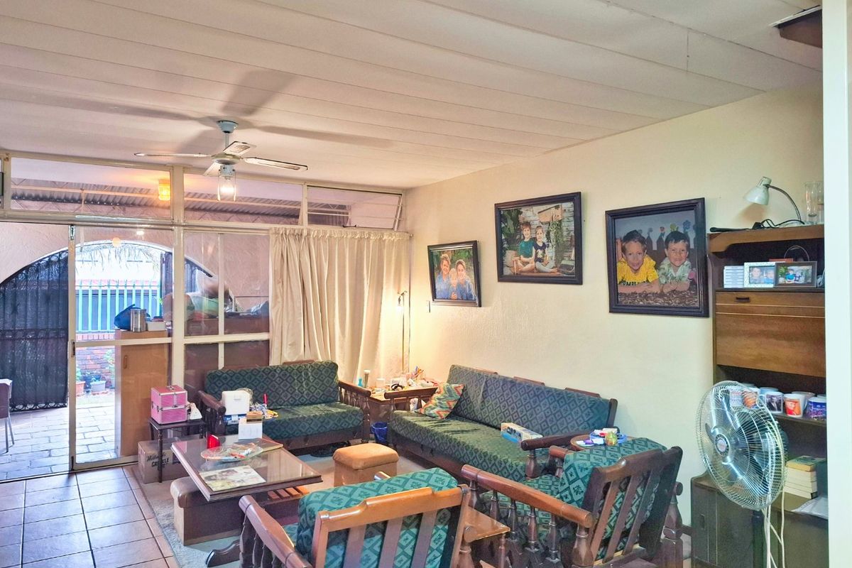 A living room featuring tiled flooring, a ceiling fan, and a sliding glass door leading to an outdoor area, with a damaged ceiling panel visible.