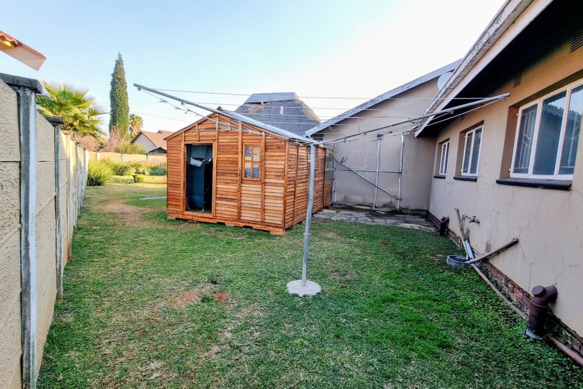 Rear garden area featuring a wooden shed, a rotary clothesline, and a precast concrete boundary wall alongside the main house structure.