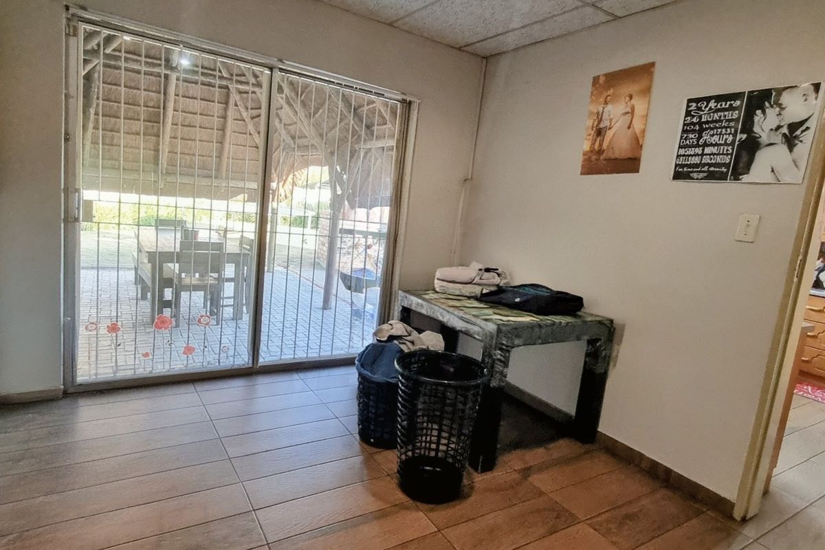 Living area featuring tiled flooring, a drop ceiling, and a sliding glass door with a security gate leading to an outdoor patio.