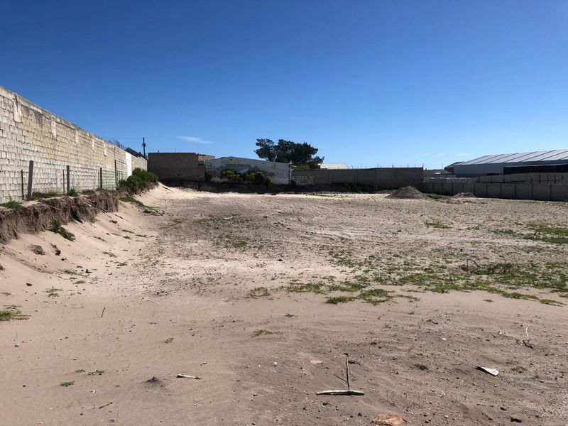 A vacant industrial plot featuring perimeter masonry walls and fencing, offering a large open space suitable for development or storage.