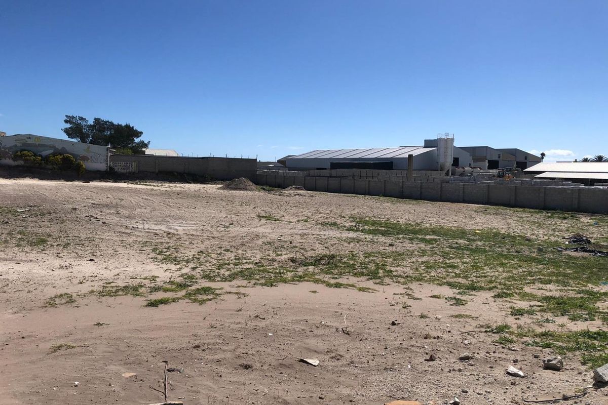 A large, vacant industrial plot of land enclosed by perimeter walls, offering significant development potential in an established industrial area.