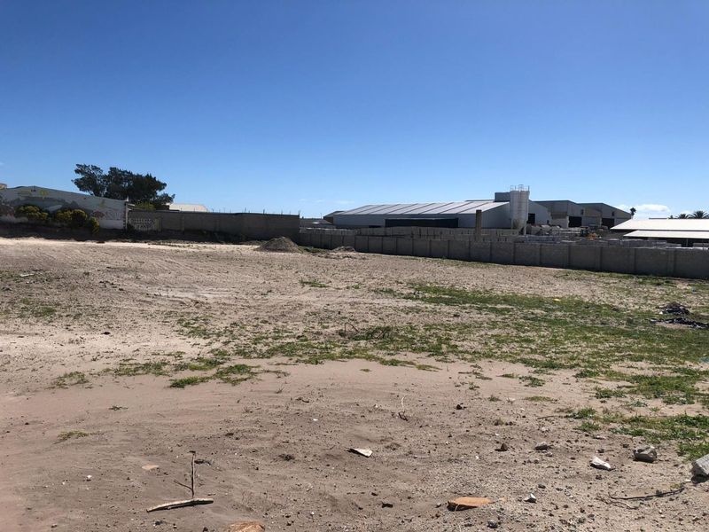 A large, vacant industrial plot of land enclosed by perimeter walls, offering significant development potential in an established industrial area.
