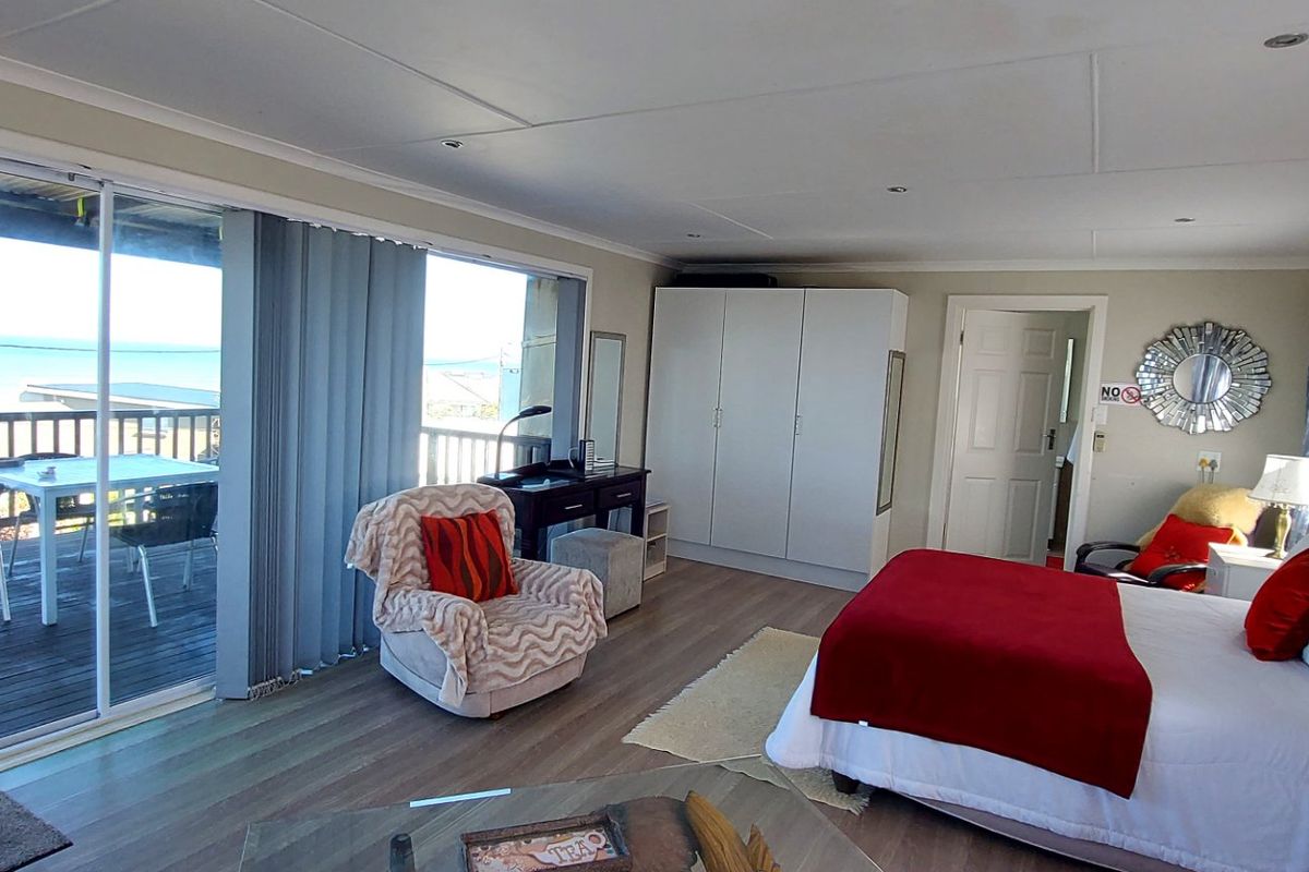 Spacious bedroom featuring laminate flooring, built-in wardrobe, and large sliding glass doors providing direct access to an outdoor balcony with scenic views.
