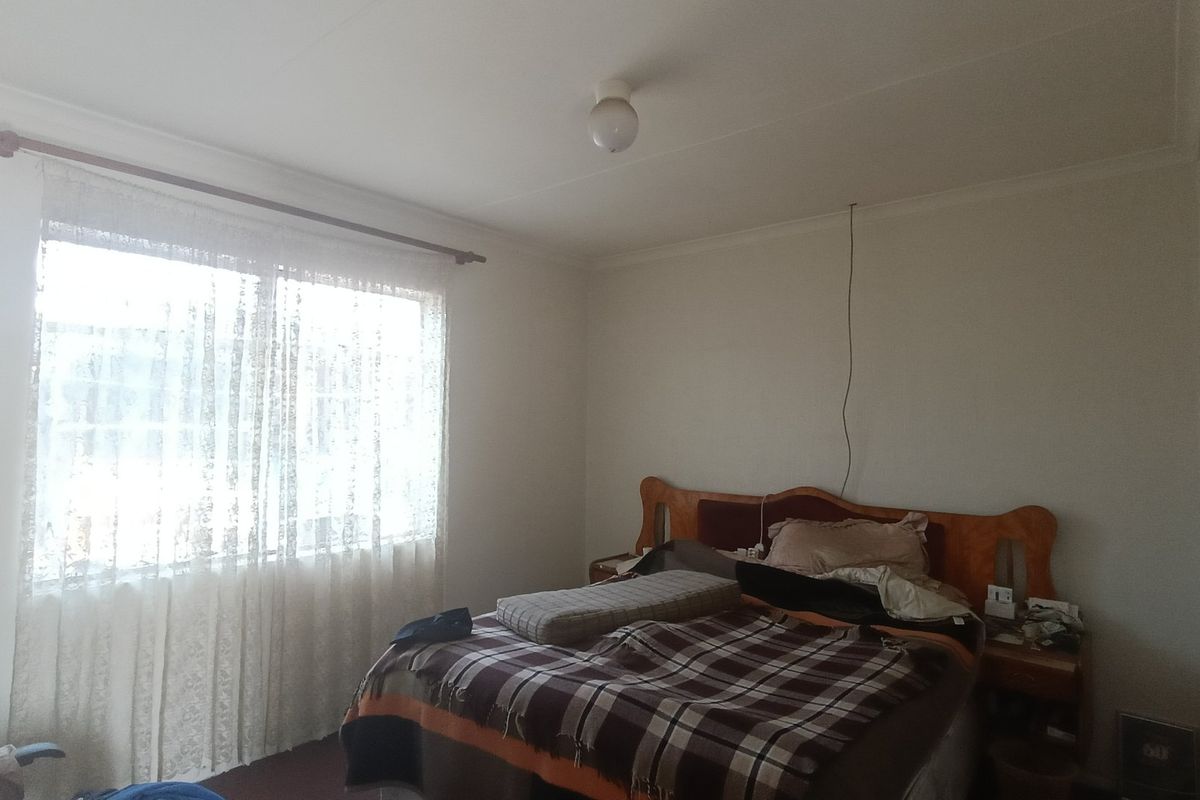 A bedroom featuring a large window with curtain rod and a ceiling light fixture, requiring minor cosmetic updates and electrical maintenance.