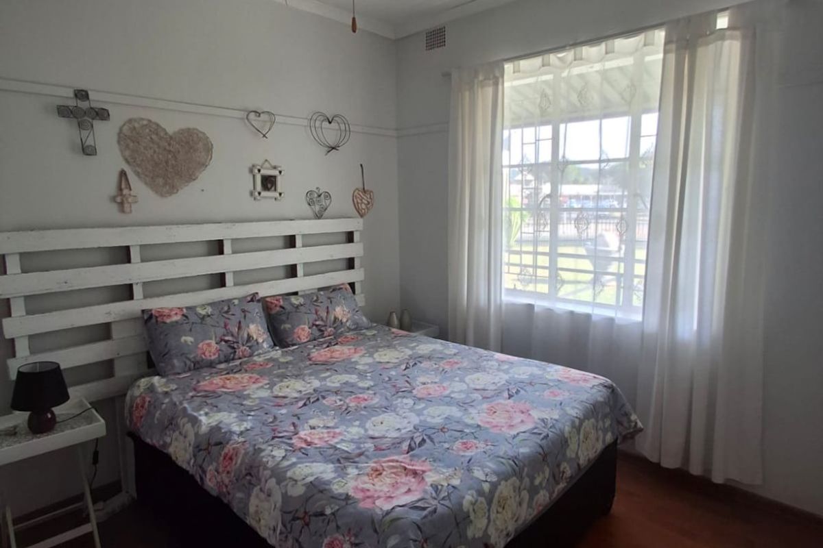 A well-lit bedroom featuring laminate flooring, a ceiling fan, and a classic picture rail, offering a comfortable and functional living space.