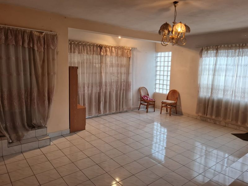 Spacious living area featuring tiled flooring, a decorative chandelier, and a glass block window, offering a blank canvas for renovation and interior design.