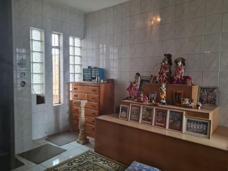 A room featuring tiled walls and glass block windows, currently utilized as a prayer space.