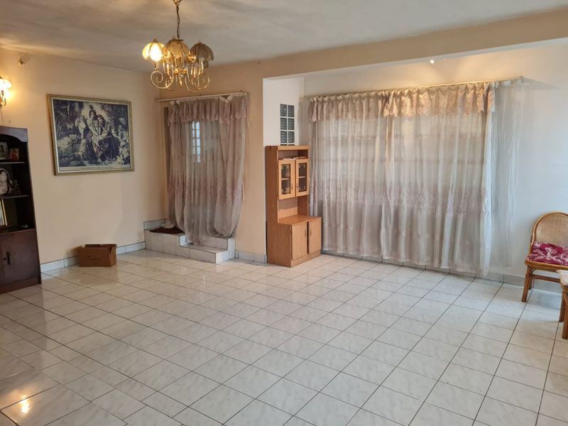 Spacious living area featuring ceramic floor tiles, a decorative chandelier, and a unique glass block feature, offering a blank canvas for modern updates.
