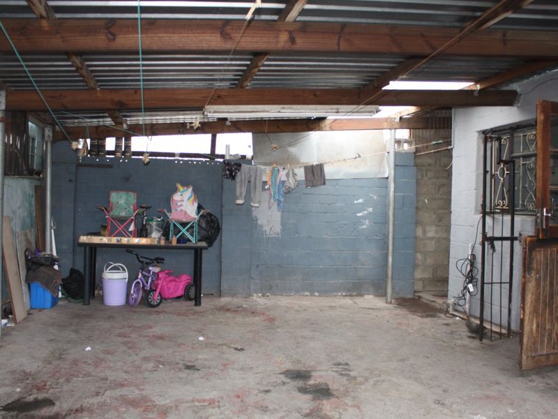 A functional garage space featuring exposed timber rafters, corrugated metal roofing, and concrete flooring, offering potential for storage or workshop conversion.