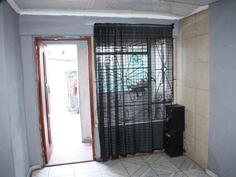 A basic interior living space featuring tiled flooring, a security gate, and direct access to an outdoor area.