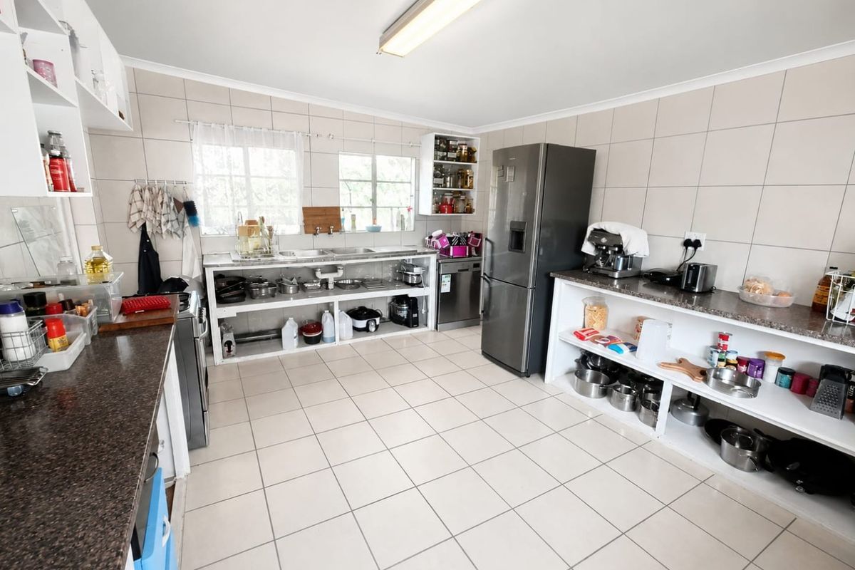 A functional kitchen featuring tiled walls and floors, granite countertops, and open shelving storage, providing a practical workspace for daily culinary activities.
