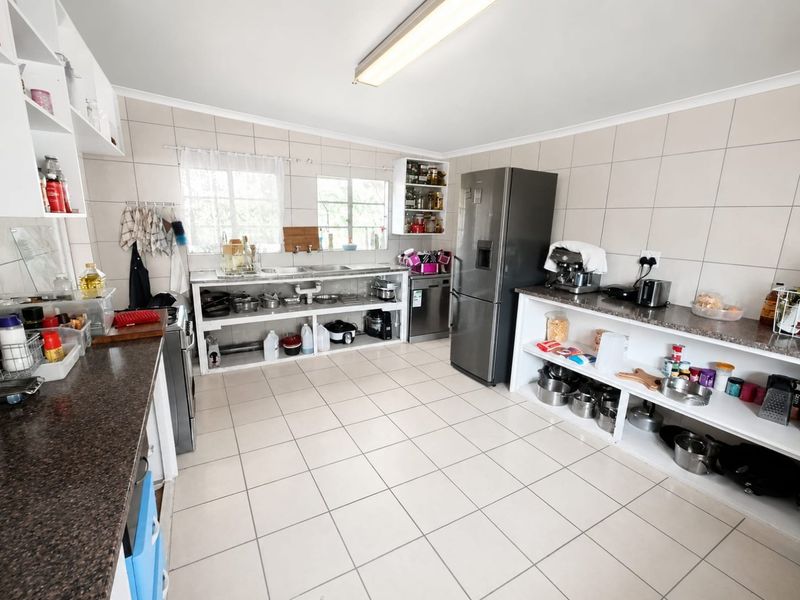 A functional kitchen featuring tiled walls and floors, granite countertops, and open shelving storage, providing a practical workspace for daily culinary activities.