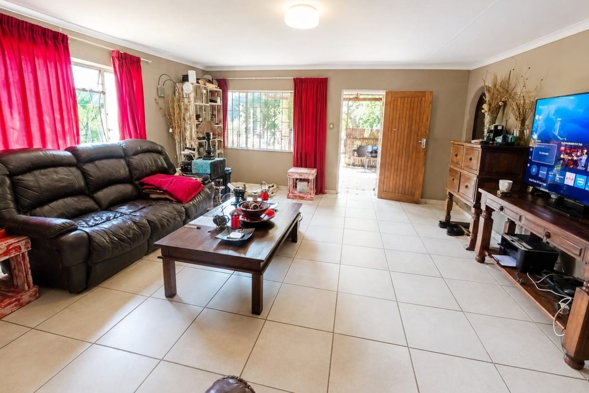 Spacious living room featuring neutral tiled flooring, large windows with natural light, and direct access to an outdoor patio area.