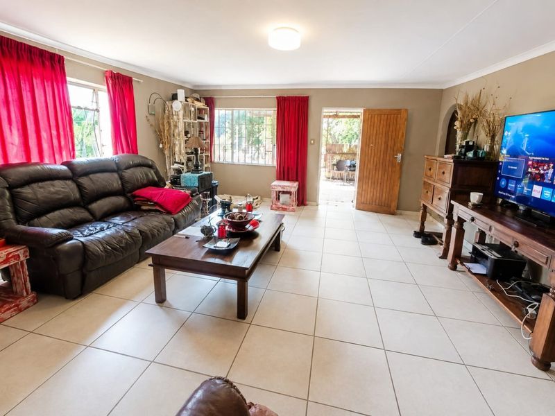 Spacious living room featuring neutral tiled flooring, large windows with natural light, and direct access to an outdoor patio area.