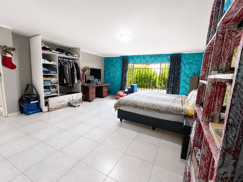 Spacious bedroom featuring tiled flooring, a built-in wardrobe, and a sliding door with security gate leading to the exterior.